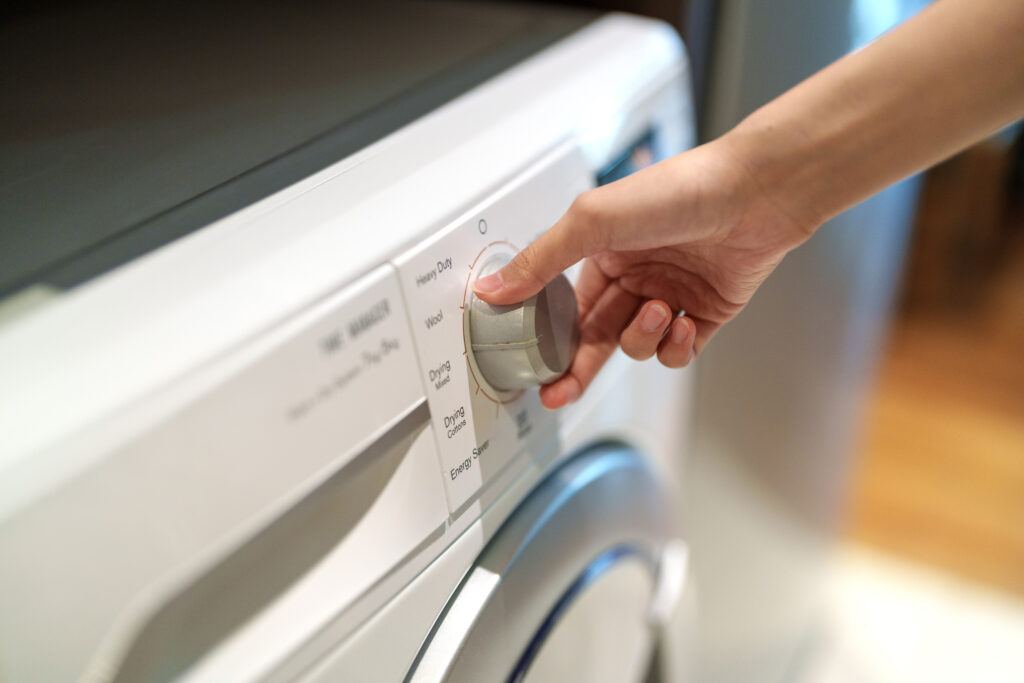 Person's hand turning washing machine knob